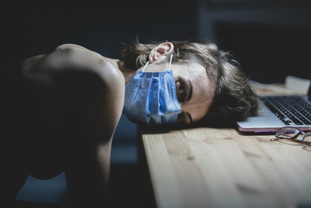 An image showing an unhealthy person laying their head down on a desk.